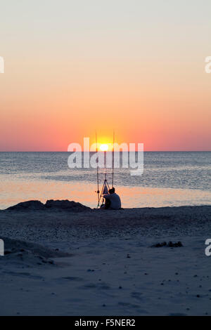 Eine Silhouette von wenigen Fischen sitzen und beobachten den Sonnenuntergang an der West Küste von Dänemark. Stockfoto