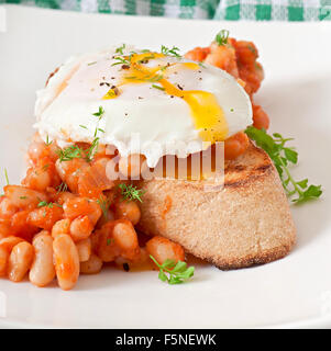 Frühstück - pochiertes Ei mit Toast, gebackene Bohnen mit Tomatensauce Stockfoto