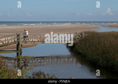 Vater und Sohn, tief in der Diskussion sind überqueren eine Brücke, den Fluss Leber an der Westküste Dänemarks überquert. Stockfoto