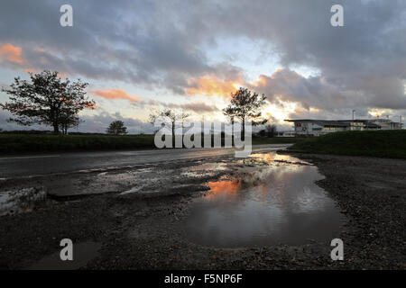 Epsom Downs, Surrey. 7. November 2015. Nach einem Tag voller Wind und Regen ging der Sturm schließlich kurz vor Dämmerung an Epsom Downs Surrey. Das warme Licht der untergehenden Sonne spiegelt sich in der riesigen Pfützen auf dem Parkplatz hinter der Tribüne. Bildnachweis: Julia Gavin UK/Alamy Live-Nachrichten Stockfoto