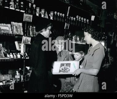 1950 - Commonwealth Besucher nach London kaufst Krönung Souvenirs mit nach Hause nehmen. Hier ist Miss Mary King, Mitarbeiterin einen Souvenir-Shop am Trafalgar Square zeigt ein Tee-Tablett verziert mit einem Farbfoto der Königin, Frau A.Taylor und ihr Sohn, Jimmy II und Tochter Judith, im Alter von 8 Jahren. Die Taylor stammen aus Bay Inseln Neuseelands. Krönung Souvenirs für Besucher aus dem Ausland: Sobald das Datum der Krönung angekündigt wurde, Hersteller begonnen, um Souvenirs und jetzt Geschenk und Souvenir-Shops in London und andere große Städte sind schon dabei einen regen Handel, e Stockfoto