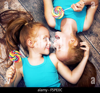 Feinen Porträt des einen Zwillings-Schwestern halten bunte Lutscher Stockfoto