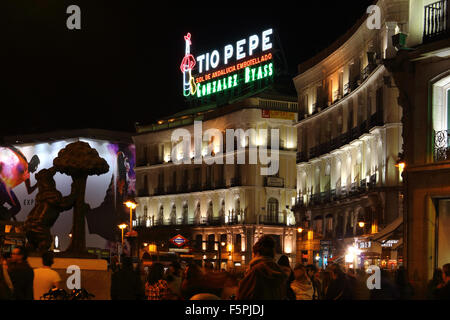 Puerta del Sol in Madrid, mit zwei seiner Symbole, der Bär und der Erdbeerbaum und die Tio Pepe Leuchtreklame in der Nacht. Stockfoto