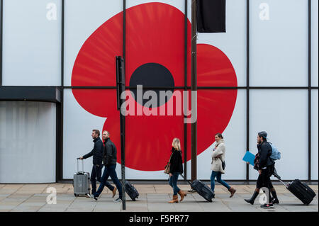 London, UK.  8. November 2015.  Touristen gehen von einem Gebäude auf der Strand, geschmückt mit einem riesigen Mohn am Remembrance Day Sonntag. Bildnachweis: Stephen Chung / Alamy Live News Stockfoto