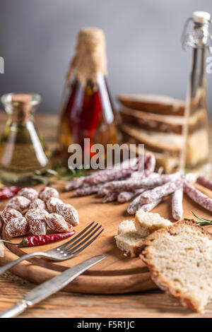 Satz von Salami Wurst mit rote scharfe Chilischoten auf Holzbrett serviert Stockfoto