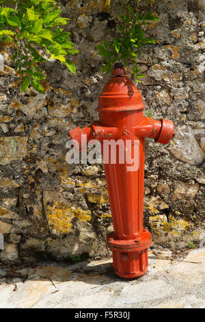 Ein rotes Feuerhydrant steht gegen eine Steinmauer in Kefalonia, Griechenland. Stockfoto