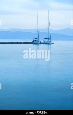 Zwei Jachten vor Anker im Hafen von Kassiopi in das kühle blaue Morgenlicht. Stockfoto