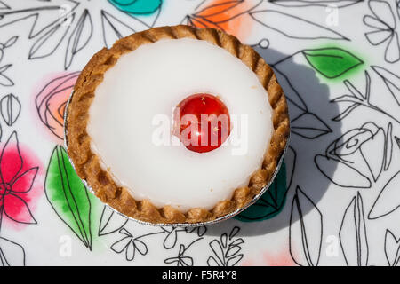 Cherry Bakewell tart Nahaufnahme auf einem blumig gemusterten Hintergrund Stockfoto