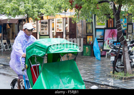 Hoi an eine alte Stadt in Vietnam. Nasse Saison und schwere Regenfälle in der Stadt. Cyclo-Rikscha-Fahrer auf der Suche nach Unternehmen Stockfoto