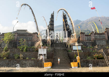 Ein Mädchen steigt die Treppen zum Pasar agung Tempel mit dem Gipfel des Vulkan im Hintergrund, in Bali, Indonesien. Stockfoto