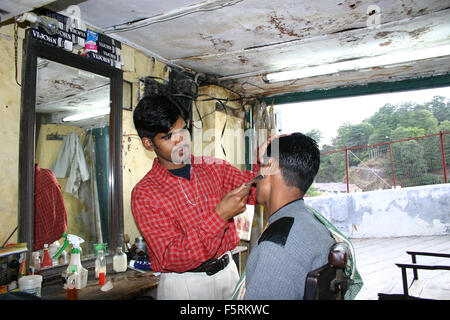 Delhi, Indien - Mai 1,2004: Ein Barbier geben eine saubere Rasur an dem Kunden in seinem kleinen Laden in Delhi. Stockfoto