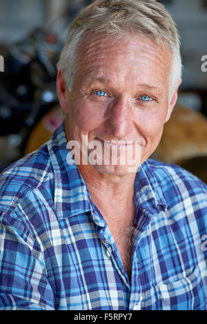 Porträt von einem reifen Alter Mann mit seinem Motorrad im Hintergrund Stockfoto