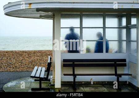 Eine Familie Schutz vor dem Regen in einer Unterkunft direkt am Meer, durch den nassen Milchglas fotografiert. Stockfoto