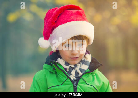 Bildnis eines Knaben mit Weihnachtsmütze im Park im Herbst Stockfoto