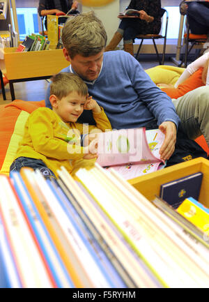 Oldenburg, Deutschland. 7. November 2015. Vitali und sein fünf-Jahr-alten Sohn David Blick auf einen neuen Atlas kurz nach die offizielle Eröffnung des 41. Kinder und Jugend buchen fair "Kibum' in Oldenburg, Deutschland, 7. November 2015. Elf Tage lang können Kinder und Eltern 2.500 neue Releases von fast 300 Verlagen durchsuchen. Foto: INGO WAGNER/Dpa/Alamy Live News Stockfoto