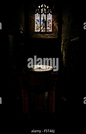 Schriftart und Buntglas-Fenster im dunklen Innenraum der St. Carantoc Kirche in Crantock Dorf Stockfoto