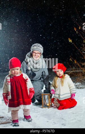 Finnland, Porträt der Großmutter mit Enkelinnen (12-17 Monate, 2-3) im Hinterhof in der Nacht Stockfoto