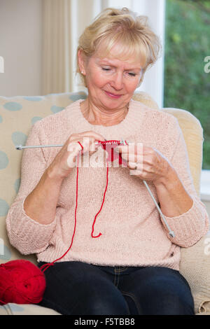 Ältere Frau sitzt im Stuhl stricken Stockfoto