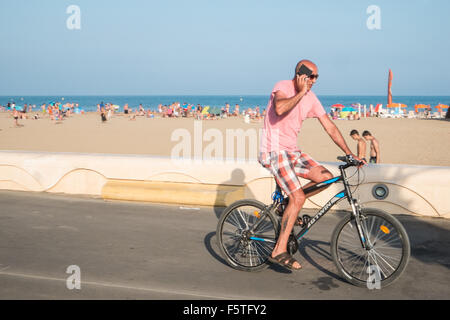 Radfahrer im Sommer auf Handy reiten, radfahren, Fahrrad, Fahrräder, durch, Meer, entlang der Promenade in Narbonne Plage, Strand, Südafrika, Frankreich, Aude, Mittelmeer, Küste, Stockfoto