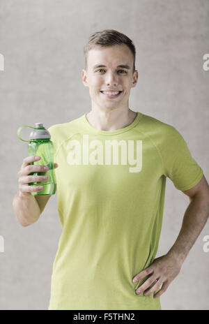 lächelnder Mann mit Flasche Wasser im Fitness-Studio Stockfoto