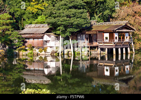 Alte traditionelle japanische Teehäuser am Rande der Gartenteich mit Spiegelungen im Wasser und Kiefer Bäume auf einen sonnigen Herbst da Stockfoto