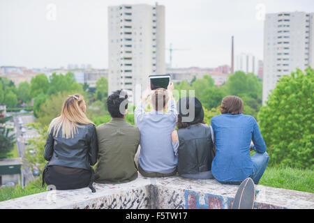 Gruppe junger multiethnischen Freunde sitzen in einer kleinen Mauer, gesehen von hinten, Blick auf den Horizont - Konzept der Zukunft, prospektive, Freundschaft Stockfoto