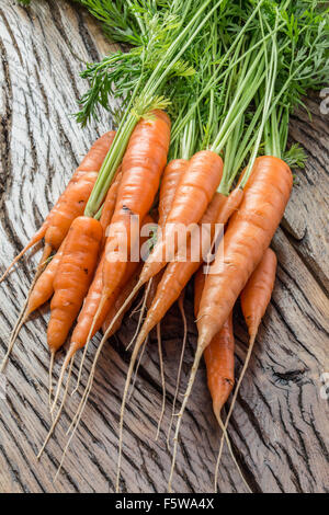 Karotten mit grün auf dem alten Holztisch. Stockfoto