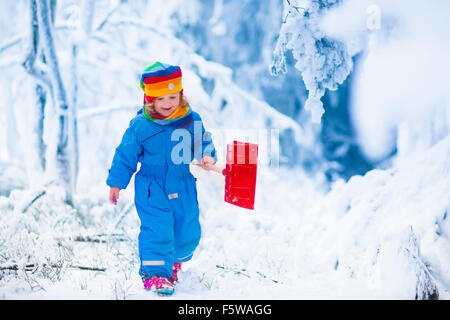 Kleines Mädchen Schneeschaufeln auf Basislaufwerks Weg. Schönen verschneiten Garten oder Vorgarten. Kind mit Schaufel spielen im Freien im winter Stockfoto