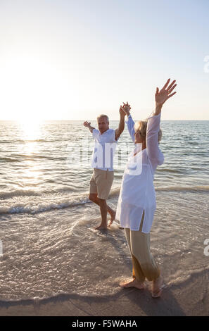 Ältere Mann und Frau Paar zusammen bei Sonnenauf- oder Sonnenuntergang auf einer wunderschönen tropischen Strand gehen Stockfoto