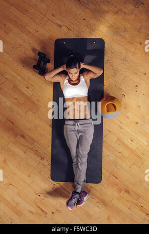 Passen Sie junge Frau liegt auf Gymnastikmatte Magen Übungen. Draufsicht der weiblichen trainieren Sie im Fitness-Studio Stockfoto