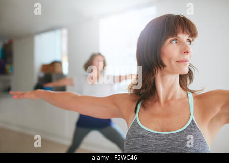 Porträt der schönen jungen Frau tut der Krieger-Pose während der Yoga-Kurs. Yoga-Lehrer Durchführung Virabhadrasana Position ich Stockfoto