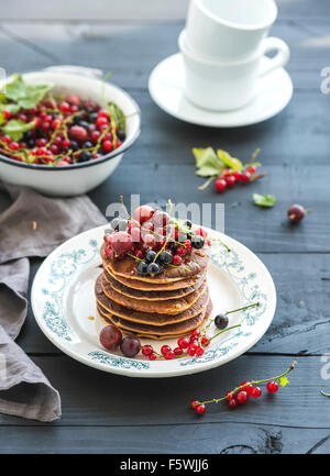 Frühstücks-Set. Buchweizen Pfannkuchen mit frischen Beeren und Honig auf rustikale Platte über schwarzer Holztisch Stockfoto