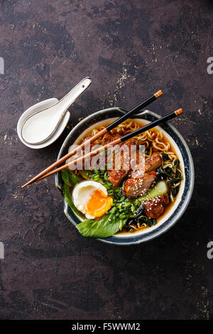 Ente Nudeln mit Ei und Pak Choi Kohl in Schüssel auf dunklen schwarzen Steinstruktur Hintergrund Stockfoto