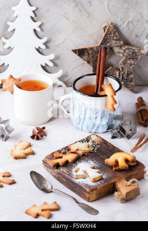 Weihnachten Spritzgebäck für Tassen, zwei Tassen heißen Tee und Zucker Pulver über Tisch mit weißer Tischdecke mit Weihnachten Deko Stockfoto