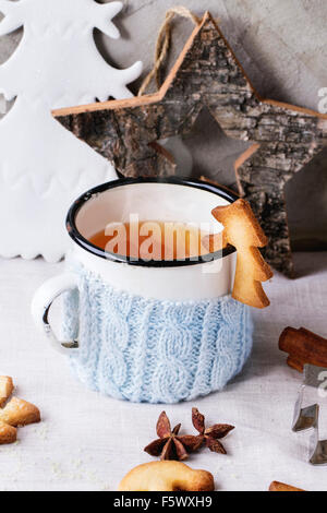 Weihnachten Spritzgebäck für Tassen, Vintage Tasse heißen Tee in gestrickten Becherhalter, Zimtstangen und Puderzucker über Tisch Stockfoto