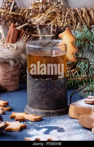 Weihnachten Spritzgebäck für Tassen in Puderzucker, Glas heißen Tee in Becherhalter auf Tisch mit blauen Tischdecke. Weihnachten d Stockfoto