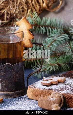 Weihnachten Spritzgebäck für Tassen in Puderzucker, Glas heißen Tee in Becherhalter auf Tisch mit blauen Tischdecke. Weihnachten d Stockfoto