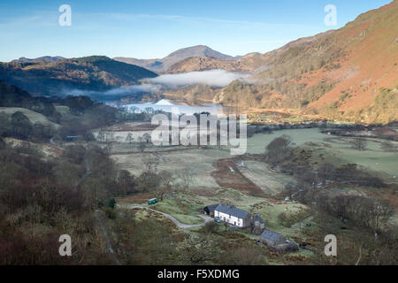 Landschaftsbild eines Sees mit frühen Morgennebel in einem grünen Tal. Morgensonne beleuchtet die umliegenden Berge Stockfoto