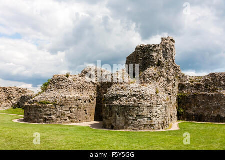 England, Pevensey Castle. Norman Schloss innerhalb der Römischen Saxon Shore fort gebaut. Ruine des Bergfrieds Basis und Grundlagen der Türmchen Eingang. Grauer Himmel. Stockfoto