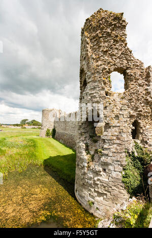 England, Pevensey Castle. Torhaus, Wassergraben und Ruinen von Norden Turm der mittelalterlichen Burg innerhalb der Römischen Saxon Shore fort gebaut. Grauer Himmel aber sonnig. Stockfoto