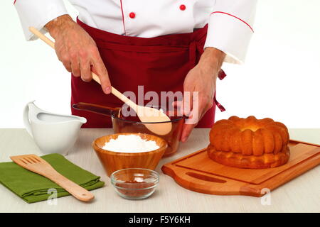 Hinzufügen von Puderzucker in Schüssel geben. Schokoladenglasur für Gugelhupf machen. Stockfoto