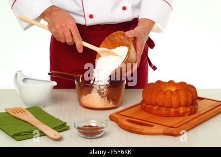 Hinzufügen von Puderzucker in Schüssel geben. Schokoladenglasur für Gugelhupf machen. Stockfoto