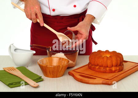Hinzufügen von Kakaopulver in Schüssel geben. Schokoladenglasur für Gugelhupf machen. Stockfoto