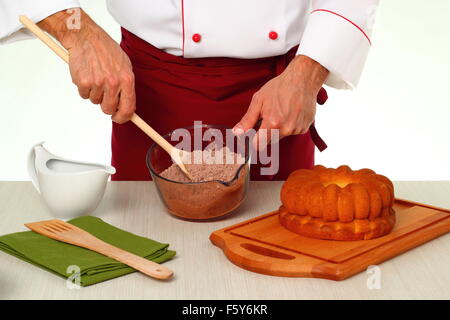 Kakao und Puderzucker mischen... Schokoladenglasur für Gugelhupf machen. Stockfoto