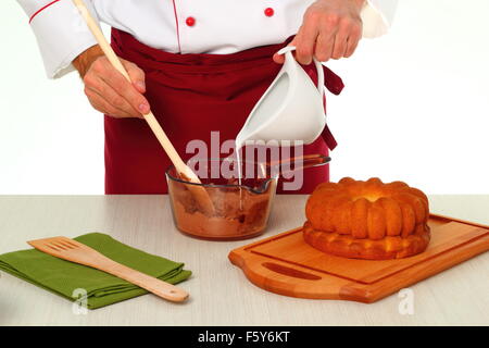 Gießen die Milch. Schokoladenglasur für Gugelhupf machen. Stockfoto
