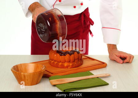Schokoladenglasur auf Kuchen gießen. Schokoladenglasur für Gugelhupf machen. Stockfoto