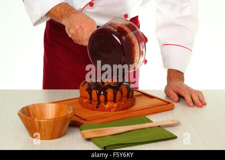 Schokoladenglasur auf Kuchen gießen. Schokoladenglasur für Gugelhupf machen. Stockfoto