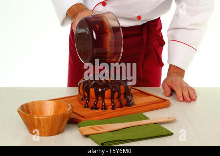 Schokoladenglasur auf Kuchen gießen. Schokoladenglasur für Gugelhupf machen. Stockfoto
