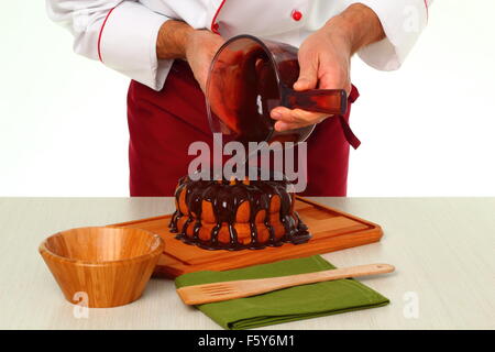 Schokoladenglasur auf Kuchen gießen. Schokoladenglasur für Gugelhupf machen. Stockfoto