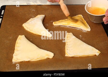 Bürsten mit Ei Glasur. So dass Schokoladencroissants mit Blätterteig Stockfoto